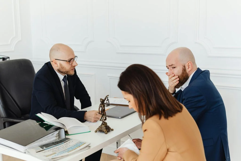 A serious legal consultation in a professional office environment involving three adults.